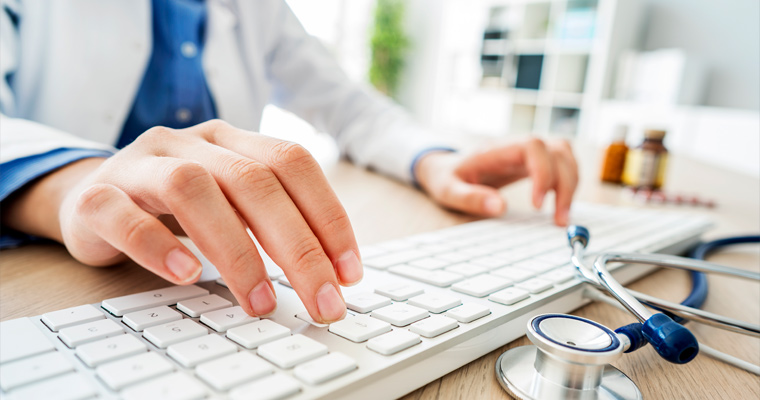 Doctor types on a computer