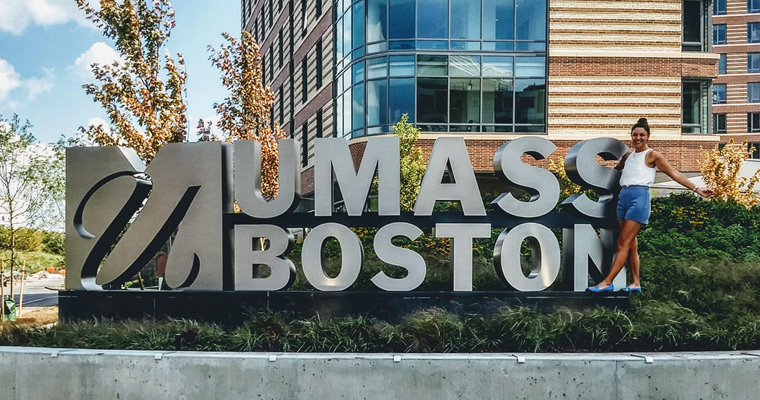 Kelsey Edmond in front of the UMass Boston sign