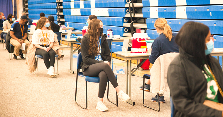 Students sitting in chairs in rows to get vaccine