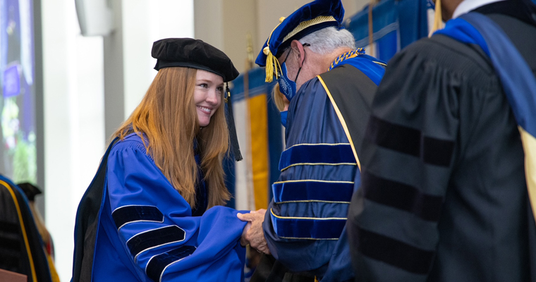 Doctoral student receives degree at hooding ceremony.