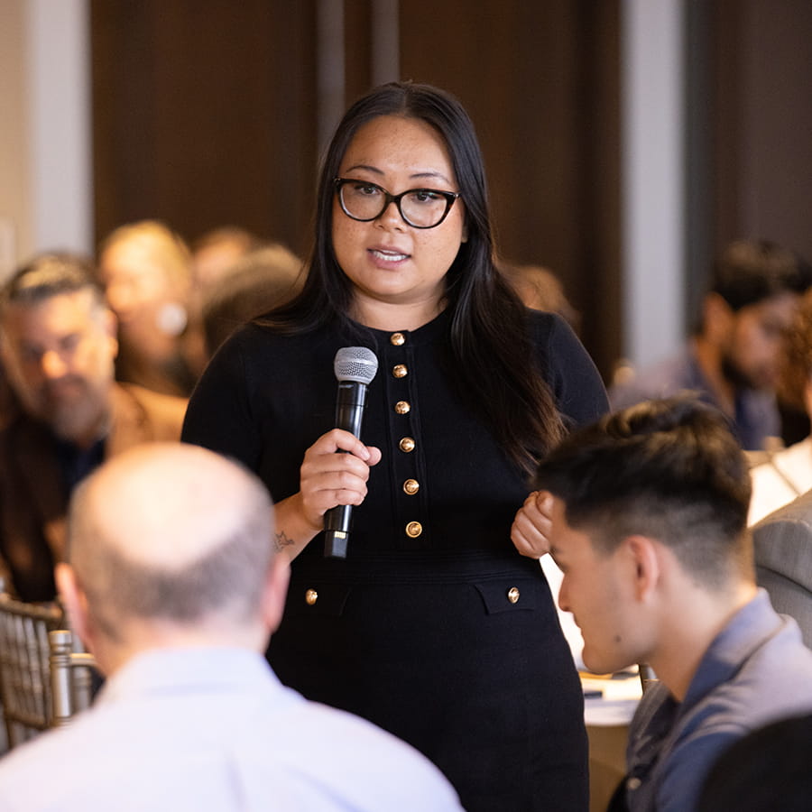 student in button down business attire dress holding microphone at conference