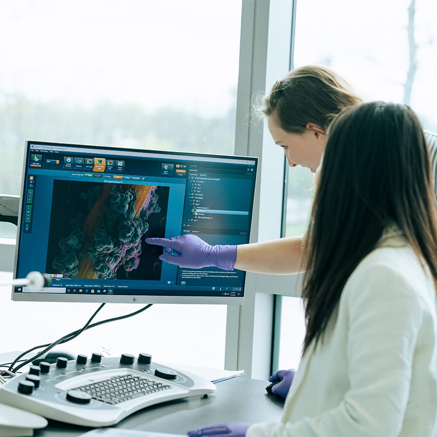 2 scientist point to a computer monitor in a research core lab.